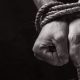 A black and white photograph of a persons hands bound in rope.