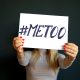 A person holding a piece of paper that reads, "#metoo."