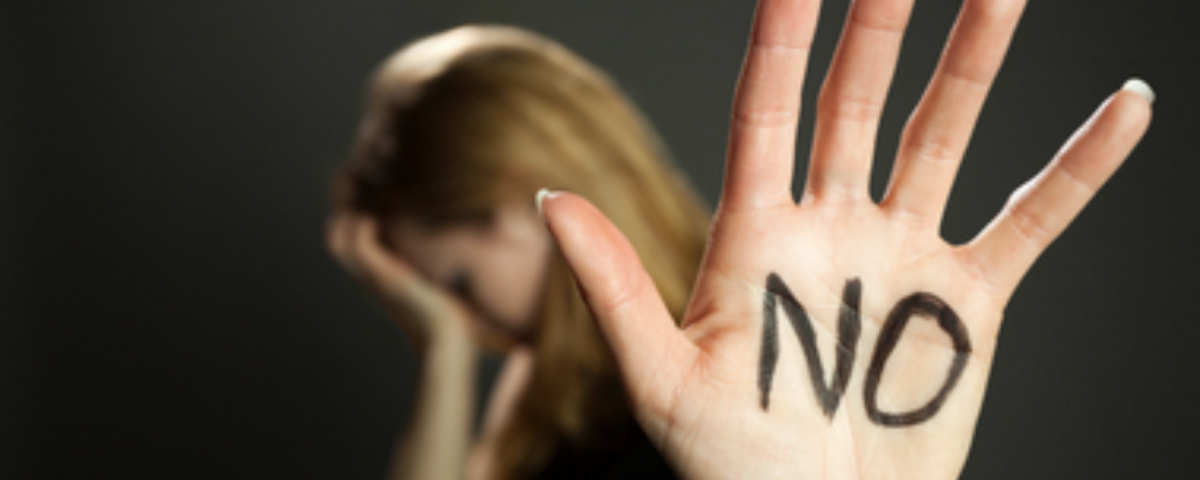 A photograph of a woman blurred holding her head in her hand, while her other hand is raised up with marker written on it stating, "NO."