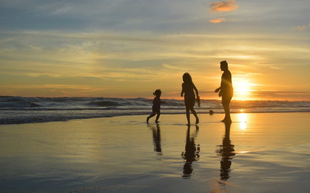 a family in silhouette on the shore line of a beach