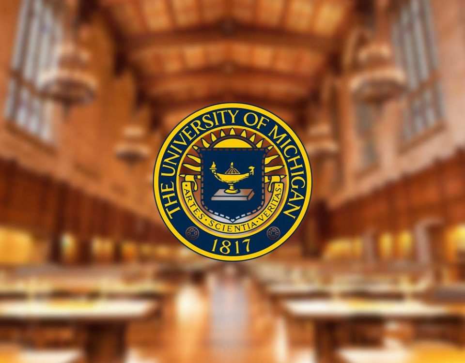 A logo for the University of Michigan. The logo is gold and royal blue, with a depiction of a lamp in the center of the logo. The logo is overlaying a photograph of a blurry room with chairs and lighting, the perspective is guiding the viewer to the end of the room.