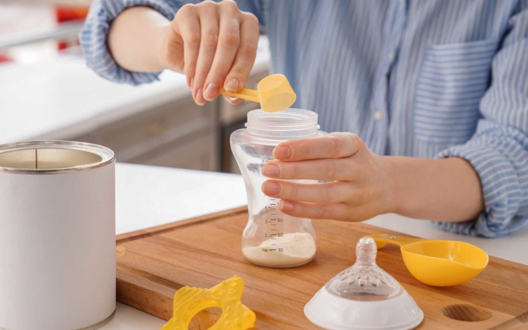a woman mixing baby formula on a cutting board with baby bottle and baby teething toy